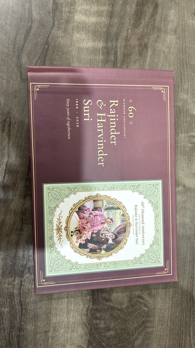 A burgundy hardcover anniversary album with gold edging and a cover portrait