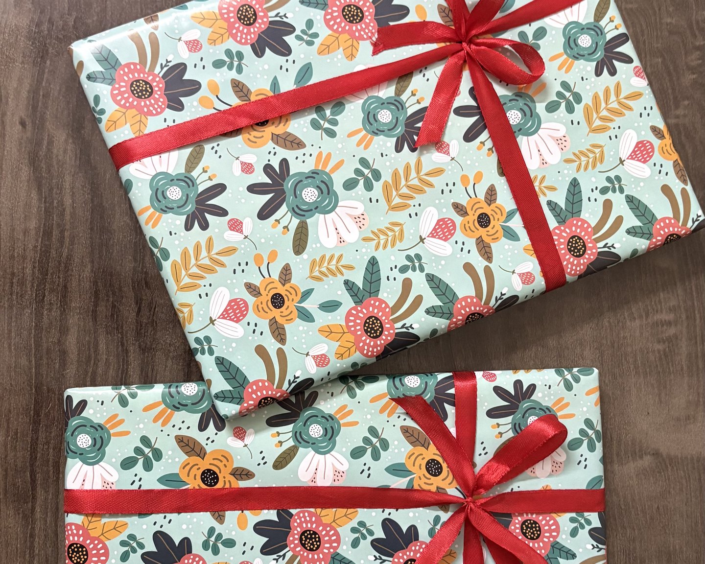 Two Apni Stories photo books, wrapped in floral paper with red ribbons